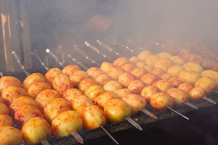 Â Potatoes on the grill. Cooking street food. Potato tubers are fried over an open fireの写真素材
