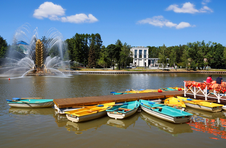 Moscow, Russia- June 13, 2019. The boat station and the Golden Ear fountain at the Exhibition of Economic Achievements. Pier with pleasure boats on the river Kamenka. In the background the Pavilion of the Museum of Cinemaのeditorial素材