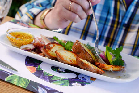 Traditional Russian snack. Fried potatoes, herring, onion and mustard. Man's hand holding a fork