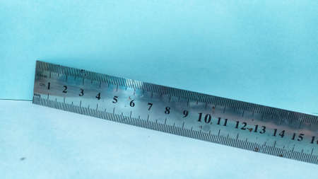 A metal ruler for measuring the length of the material on a blue backgroundの写真素材