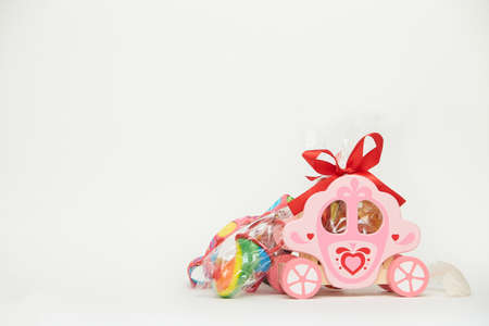 Children's toy wooden carriage toy with colorful rainbow candies and decorative red bow. Gift for kids and lovers isolated on white background. Copy spaceの写真素材