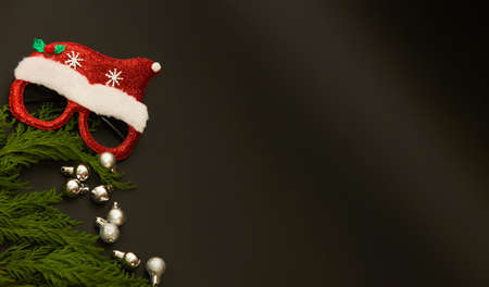 New Year ball with santa glasses and branch of Christmas tree on dark background. Xmas backdrop with space for text. Noel design.の写真素材