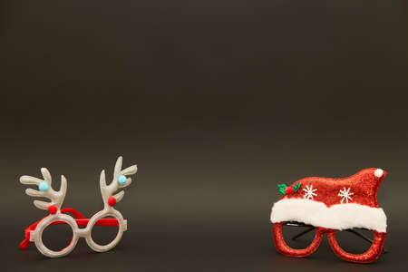 two pairs of Christmas glasses on dark background. Xmas backdrop with space for text. Noel design.