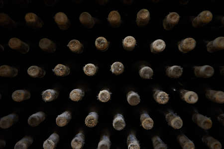 perspective view closeup of stacked aged wine bottles ancient collection covered with soft black...
