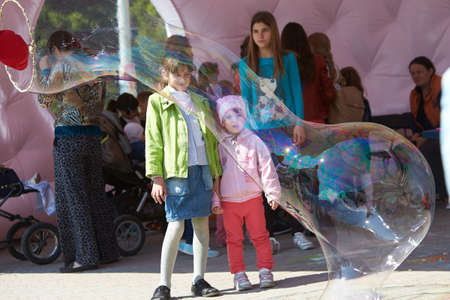 Clown hold shows for children at the public event. Big soap bubbles show clowns.