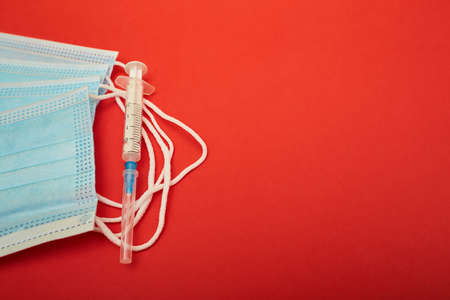 Face mask and medical syringe on the red background. Coronavirus.  close upの写真素材