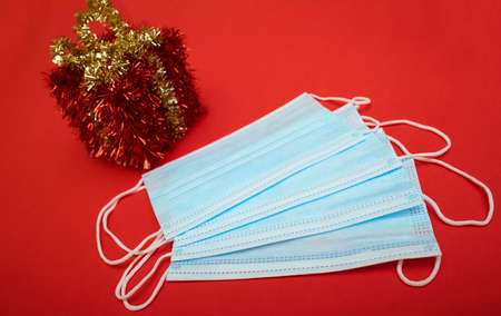 Face mask and gift box on the red New Year background. Corona virus Christmas background. Close up