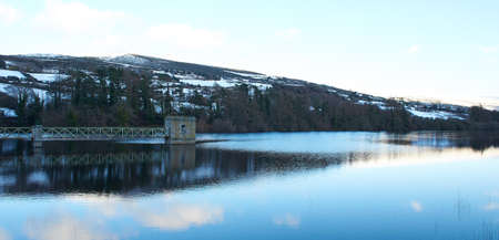 Small artificial lake on the irish mountain. panoramic snow winter dark sunset