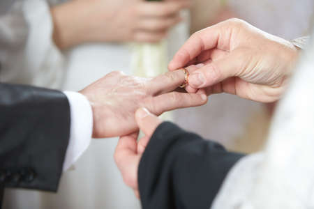 Priest puts on ring on brides and grooms finger during church wedding ceremony. Exchange of rings. Marriage concept. Wedding ceremony, bride, groom, exchanging ringsの写真素材