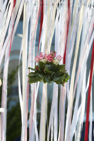 A pot with cute pink flowers hanging in the air with decorative tapes on the background.の写真素材