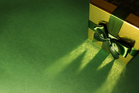 green gift box with gold cover and green ribbon bow, isolated on green background. Christmas pictureの写真素材