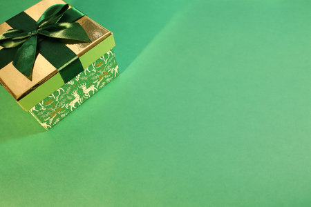 green gift box with gold cover and green ribbon bow, isolated on green background. Christmas pictureの写真素材