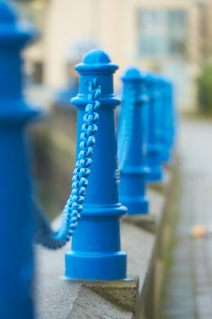 Beautiful fencing of sidewalk in form of posts with blue iron chainsの写真素材