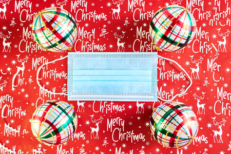 Face mask and festive decorations on the red New Year background. Corona virus Christmas background....