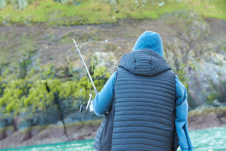 fisherman is fishing in open sea from the boat on the island background.の写真素材