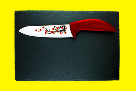 Red knife ceramic on the slate stone a yellow background.の写真素材