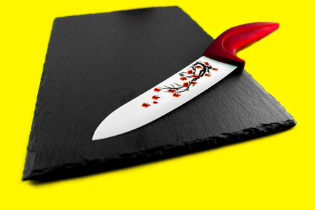 Red knife ceramic on the slate stone a yellow background.の写真素材
