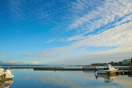 Boats in harbor with blue colorful cloudy sky in background.