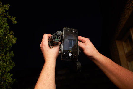 Rifle scope connected at mobile phone in a man's hands.