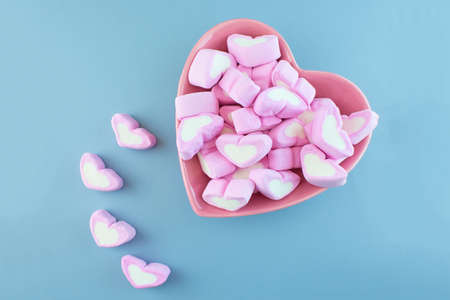 Pink heart-shaped marshmallow isolated on blue background.の写真素材