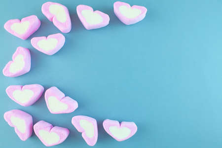 Pink heart-shaped marshmallow isolated on blue background.の写真素材