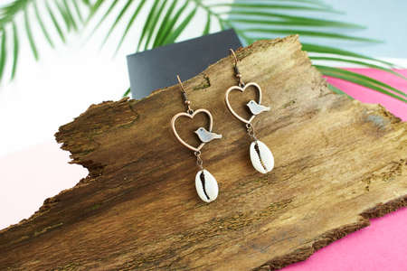 Beautiful vintage earrings on dry tree bark isolated on blue, pink background.の写真素材