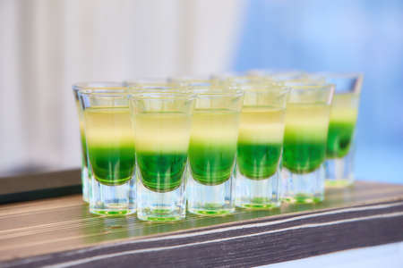 Layered Cocktail Shooter made of Absinthe, Lemon Fresh, Grenadine. Green cocktails at the club....