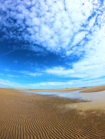 Beautiful sandy beach with bright blue sky and big clounds.
