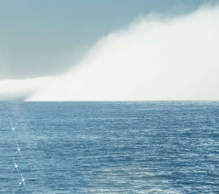 Big isolated foggy cloud on the sea. Foggy weather with detail of a sunlight reflecting in...