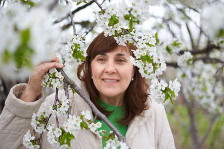 Beautiful elderly woman in blooming cherry garden.の写真素材