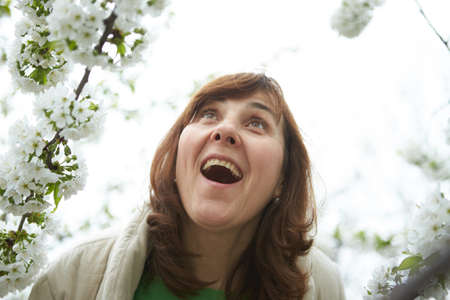 Beautiful elderly woman in blooming cherry garden.の写真素材