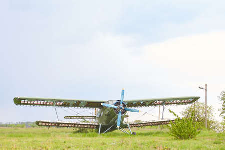 Abandoned aircraft plane standing in the field against cloudy blue sky. Small propeller plane at the...