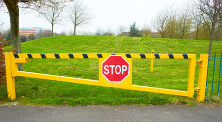 Yellow barrier with red stop sign on the entrance in park.