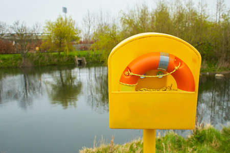Orange lifebuoy in box at the edge of the pond.の写真素材
