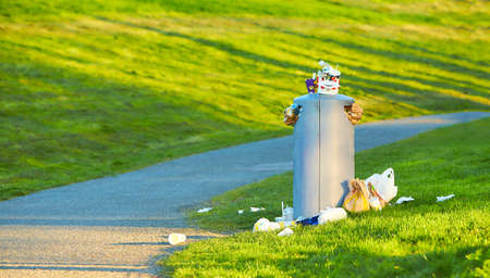 Dublin, Ireland - 04.09.2021: Full rubbish bin with garbage from plastic bottle and glasse, paper glasse for drinks in public park.のeditorial素材