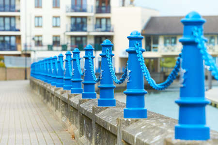 Beautiful fencing of sidewalk in form of posts with blue iron chainsの写真素材