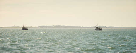 Two fishing boat, trawlers fishing Razor fish in an open Irish sea. Food industry, traditional...