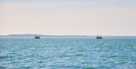 Two fishing boat, trawlers fishing Razor fish in an open Irish sea. Food industry, traditional craft, environmental damage concepts.の写真素材