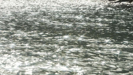 Detail of a sunlight reflecting in glittering sea. sparkling in water - background. sea water with sun glare and ripple. Powerful and peaceful nature concept.の写真素材