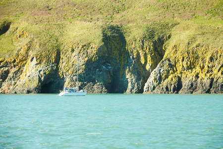 A yacht in irish sea with green island in background.の写真素材