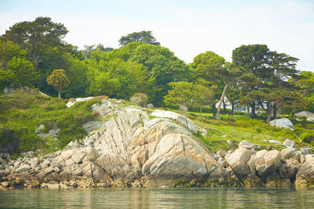 View from the sea to the greeny cliffs with exotic trees, moss and blue sky.の写真素材