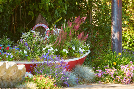 Beautiful wooden boat full with bright flowers in the street like decorative element.
