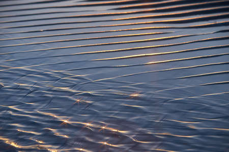 Sand waves texture with water on the sea beach. Yellow sand texture for background.