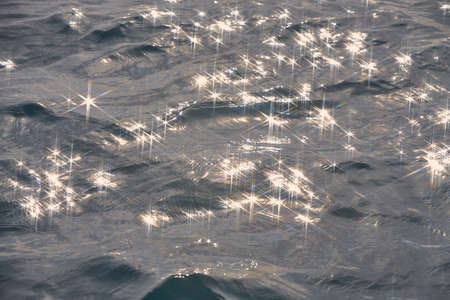 Detail of a sunlight reflecting in glittering sea. sparkler in water - background. sea water with sun glare and ripple. Powerful and peaceful nature concept.の写真素材