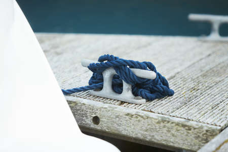 Mooring rope and bollard on sea water and yachts background