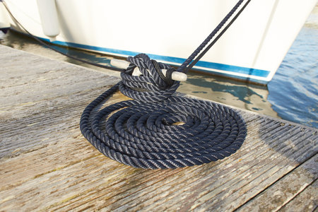 Mooring rope and bollard on sea water and yachts background