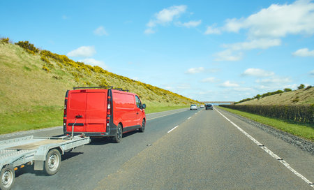 Rear view of cars driving on motorway, Ireland. Road with metal safety barrier or rail. cars on the asphalt under the cloudy blue sky. Highway traffic.の写真素材