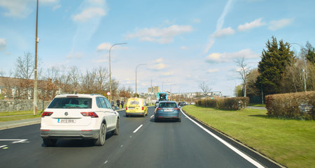 Tallaght, Ireland - 04.03.2022: Rear view of cars driving on street road, Ireland. Road with metal safety barrier or rail. cars on the asphalt under the cloudy blue sky. Highway trのeditorial素材