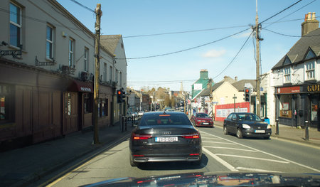 Naas, Ireland - 04.03.2022: Rear view of cars driving on street road, Ireland. Road with metal safety barrier or rail. cars on the asphalt under the cloudy blue sky. Highway traffiのeditorial素材