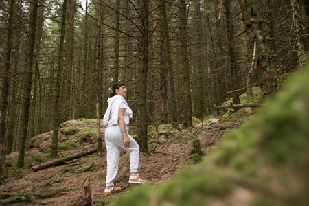 Caucasian woman in a sports clothes in irish pine forest. Touristic place. Traveling and climbingの写真素材